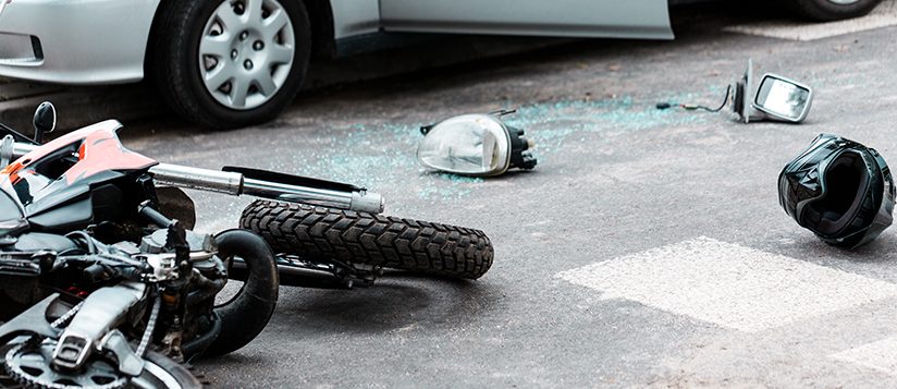 Motocicleta volcada y casco en la carretera después de una colisión con un automóvil