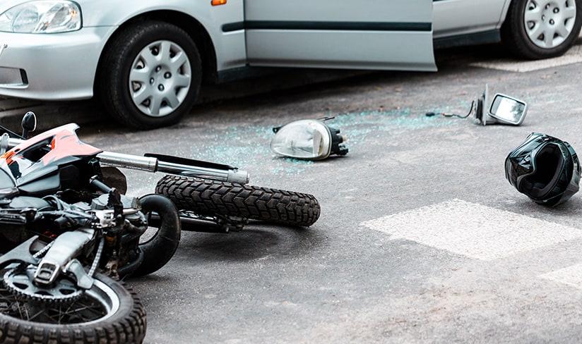 Motocicleta volcada y casco en la carretera después de una colisión con un automóvil
