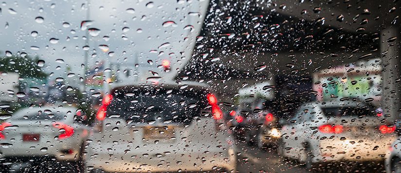 Tráfico en día lluvioso con vista de la carretera a través de la ventanilla del coche con gotas de lluvia