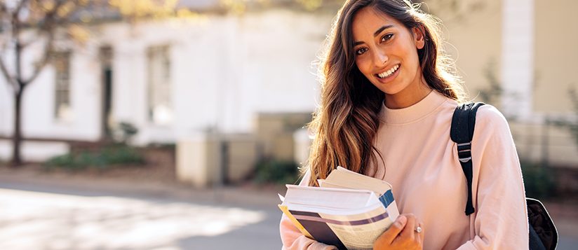 Estudiante universitario con mochila y libros al aire libre en el campus universitario